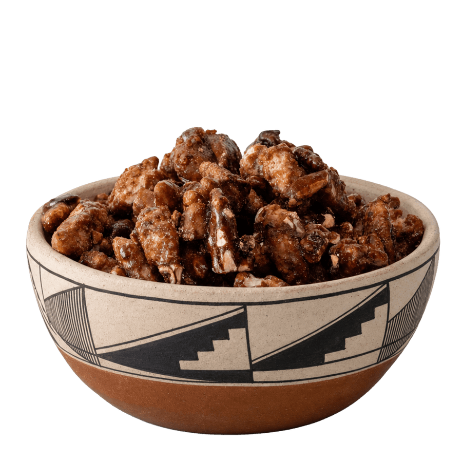 Glazed candied pecans in a Southwestern black-and-cream patterned ceramic bowl