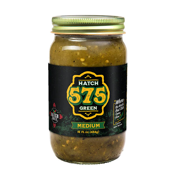 A jar of Hatch 575 Green Chile Sauce with a medium spice level, featuring a black label and green cap, isolated on a white background.