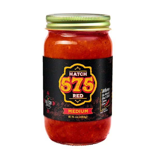 A jar of authentic Hatch 575 Red Chile Sauce with a medium spice level. The label is black and red, featuring bold text and a green lid on top of the jar.