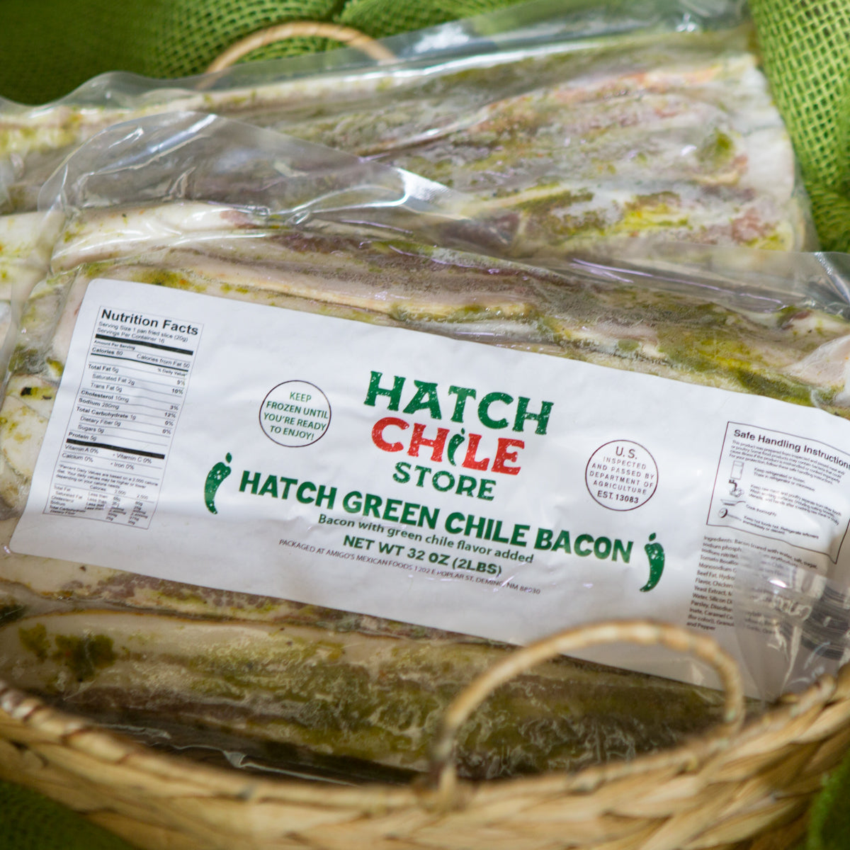 Packages of Hatch Green Chile Bacon in a wicker basket with a green cloth background, emphasizing the nutrition label and product details.
