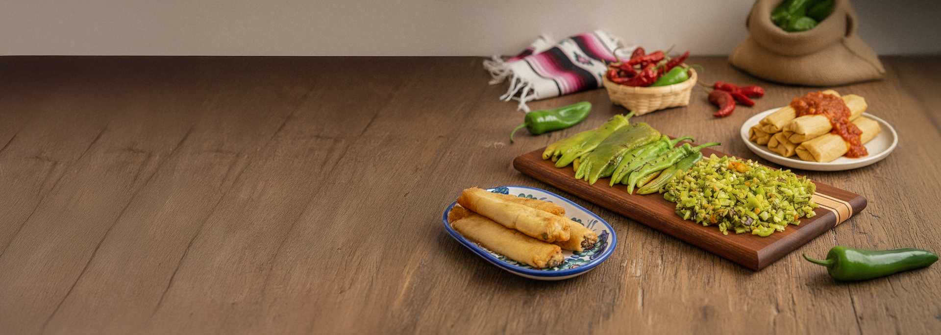 Plated hatch chile with rellenos and tamales on a wooden table