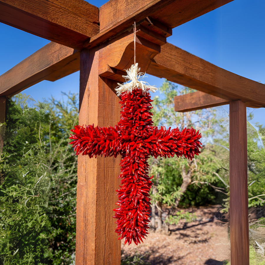 Red chile pequin cross hanging on a wooden pergola