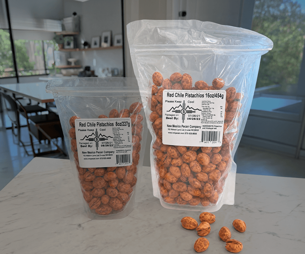 Red chile pistachios in 8 oz and 16 oz resealable bags with loose nuts nearby