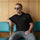 Model wearing the black Hatch Chile Store premium polo, seated