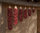 Dried red chile ristras in graduated lengths on adobe wall, second-largest highlighted