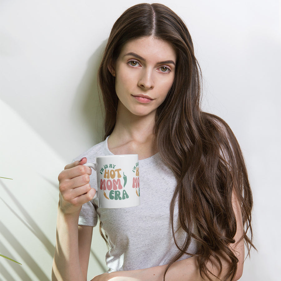 Era Mug — glossy ceramic mug, 11 oz in white, held by a model