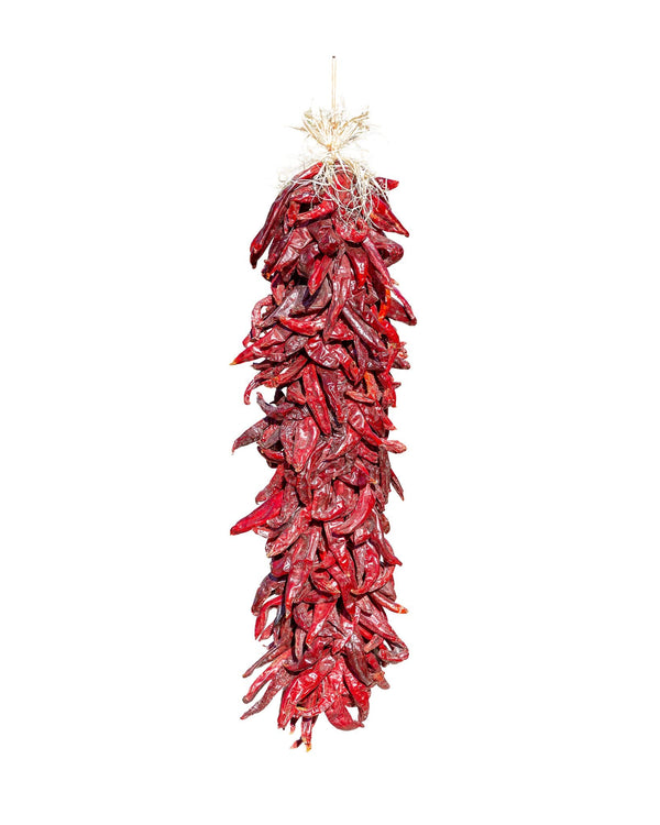 A Traditional Sandia Ristra, which is a hanging decoration made of numerous bright red chili peppers, against a white background.