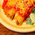 Chicken chimichangas topped with green chile sauce and shredded cheese, garnished with lime and cilantro