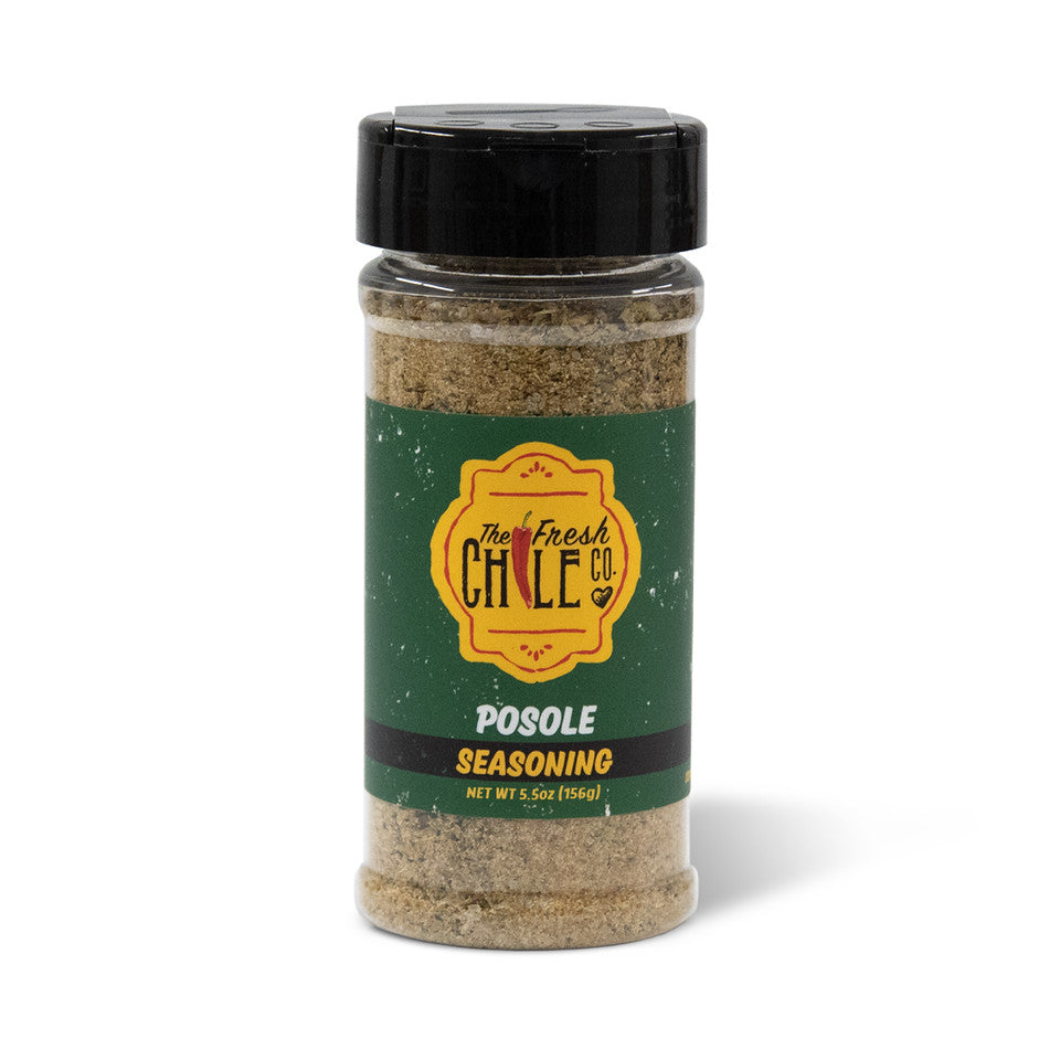A jar of Posole Seasoning against a white background, showcasing a green and yellow label, with visible ground cumin seeds in the seasoning.