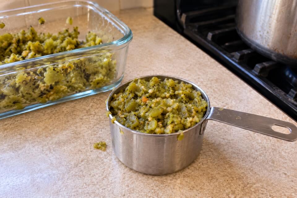Thawed chopped green chile in a metal measuring cup