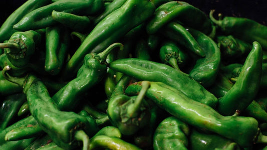 A close pile of glossy dark green fresh chile pods
