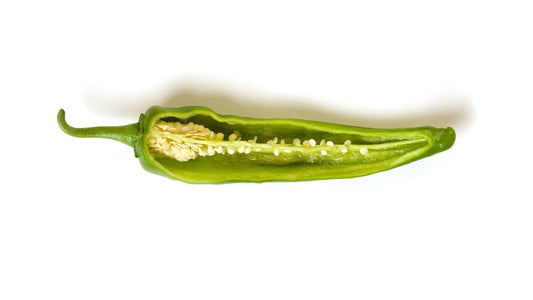 A green chile pod sliced open lengthwise to show the pale ribs and seeds inside, on a white background