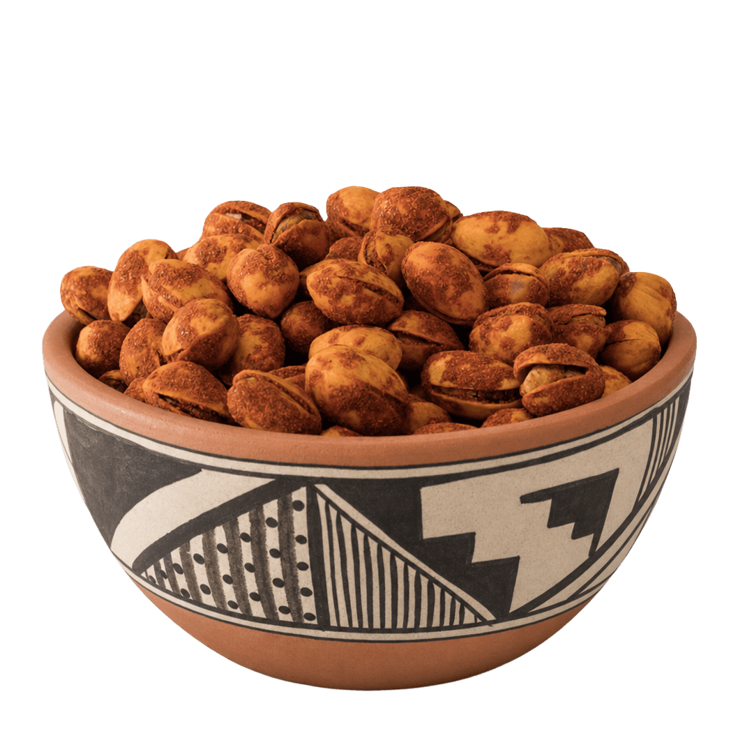 Red chile-dusted pistachios in shell in a Pueblo-patterned terracotta bowl
