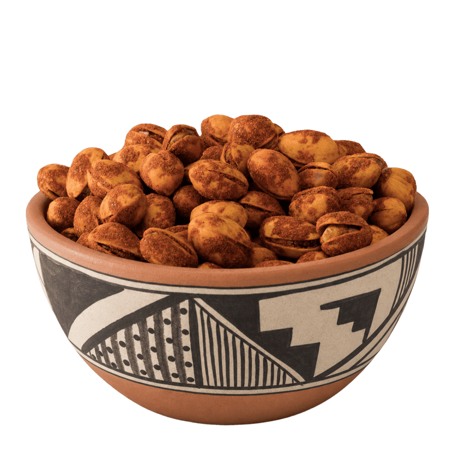 Red chile-dusted pistachios in shell in a Pueblo-patterned terracotta bowl