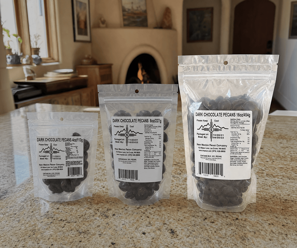 Dark chocolate pecans in 4, 8, and 16 oz resealable bags on a kitchen counter