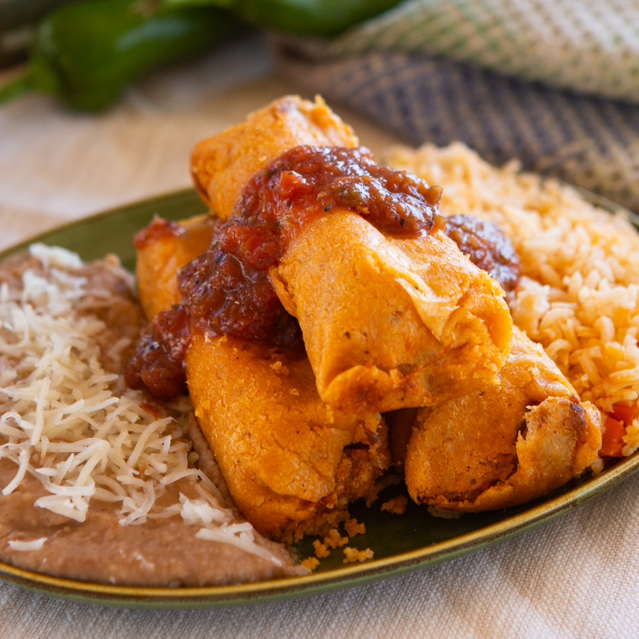 Close-up of red chile pork tamales topped with salsa