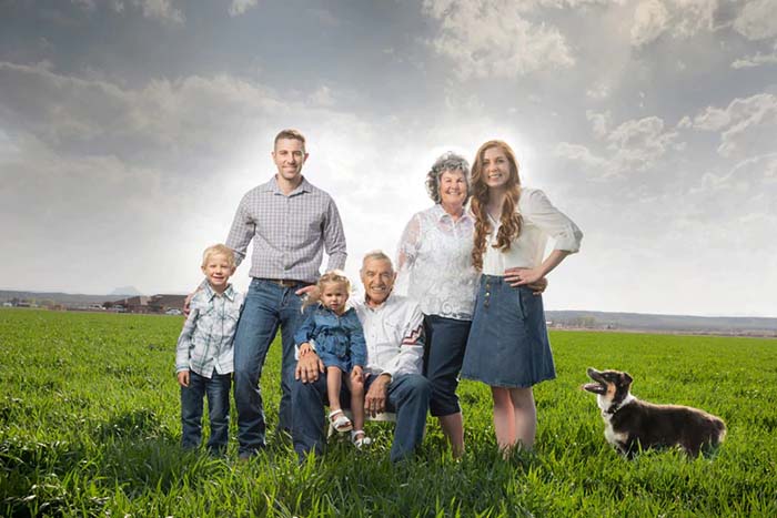 Three generations of the family that runs Hatch Green Chile in an open meadow with their dog.