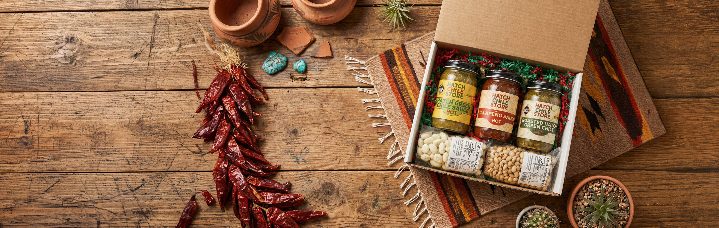 Hatch Chile Store gift box with salsa jars on rustic wooden table with dried chile ristra