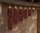 Dried red chile ristras in six graduated lengths hanging on an adobe wall