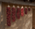 Dried red chile ristras in graduated lengths on adobe wall, fourth size highlighted