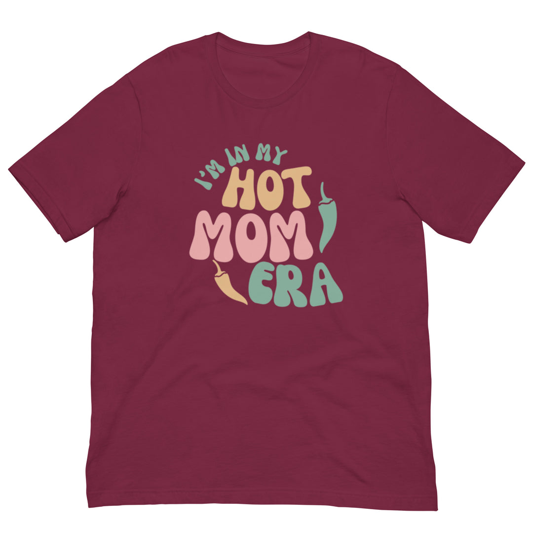 A maroon breathable Era Shirt with the phrase "in my hot mom era" printed in colorful, stylized letters on the front.