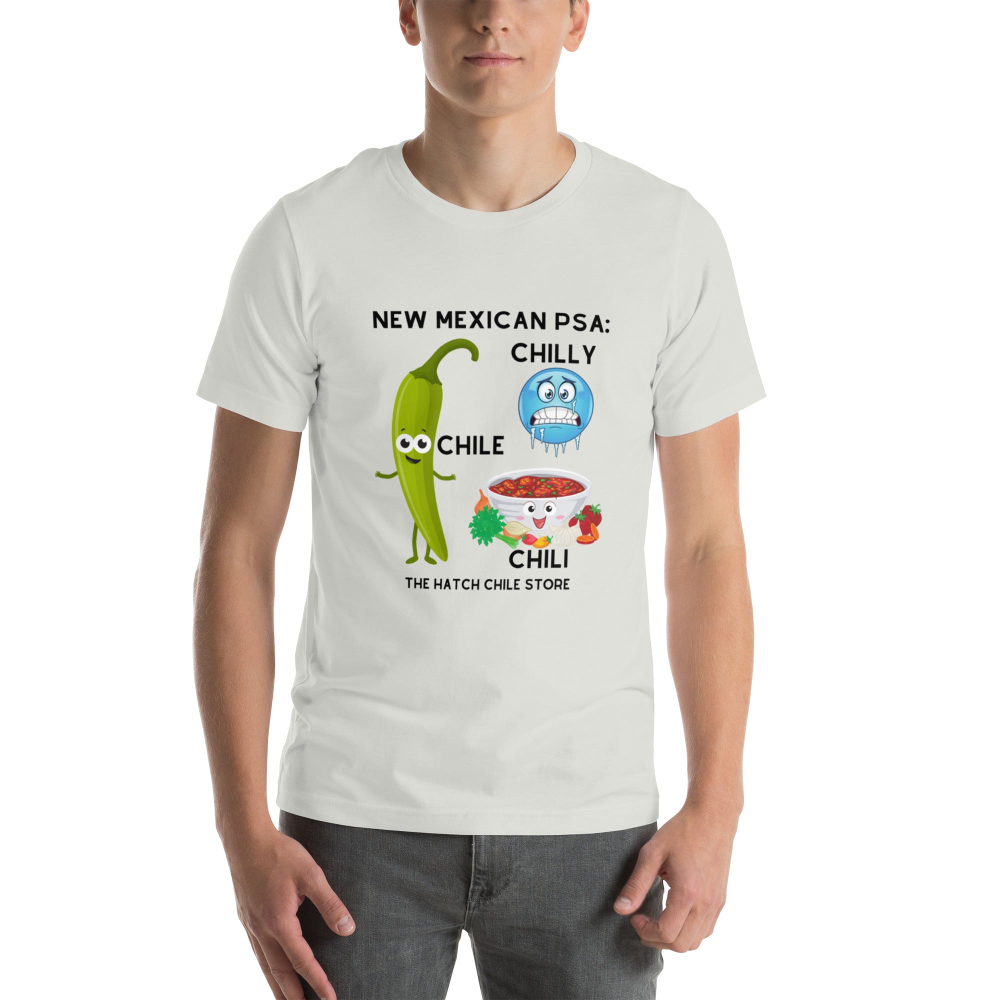 A man in a white, lightweight PSA Shirt featuring a quirky cartoon of a green chili pepper and a chilly weather scene with the text "New Mexican PSA: Chilly Chile - The Hatch Chile Store.