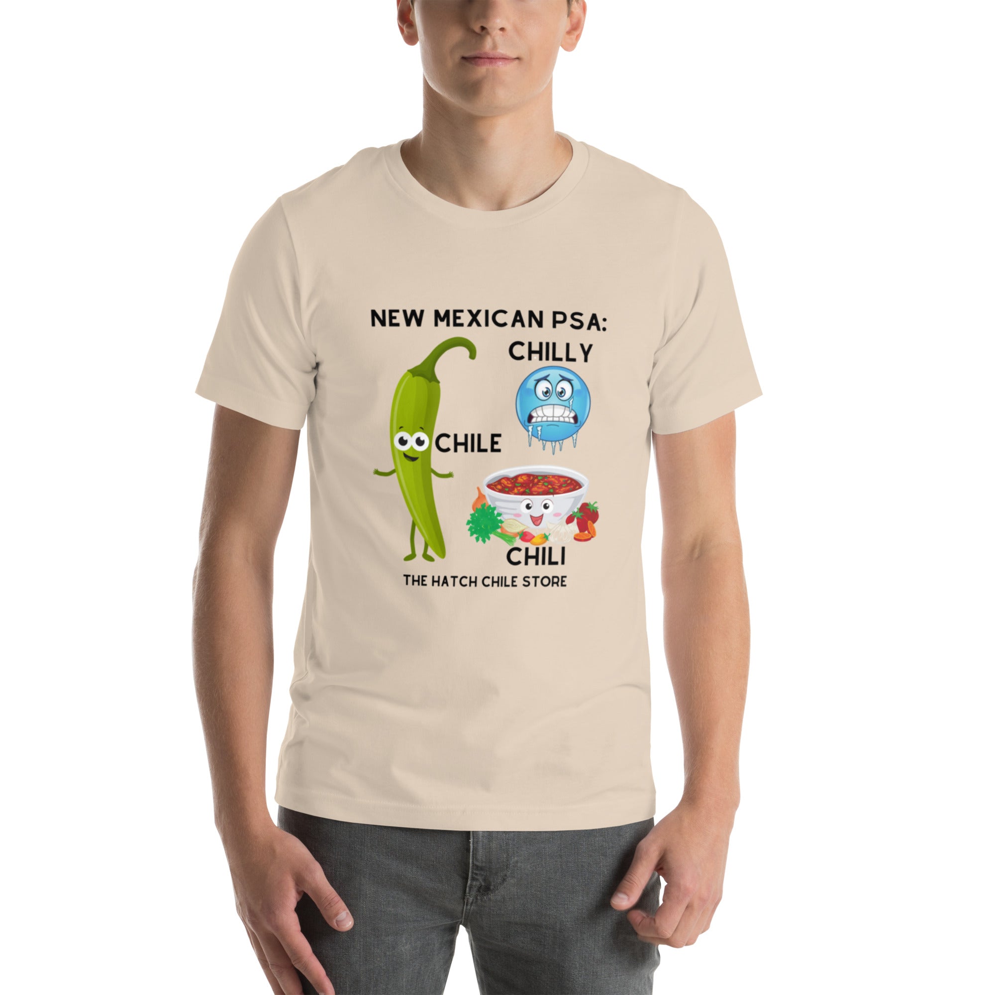 Young man wearing a lightweight, beige PSA shirt with a humorous design featuring cartoon chili peppers and the text "new mexican psa: chilly chile." The design highlights a play on words related to.