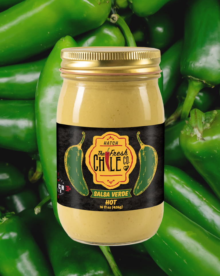 A jar of Hot Salsa Sampler, surrounded by fresh green chili peppers, displayed prominently against a background of the same chilies.