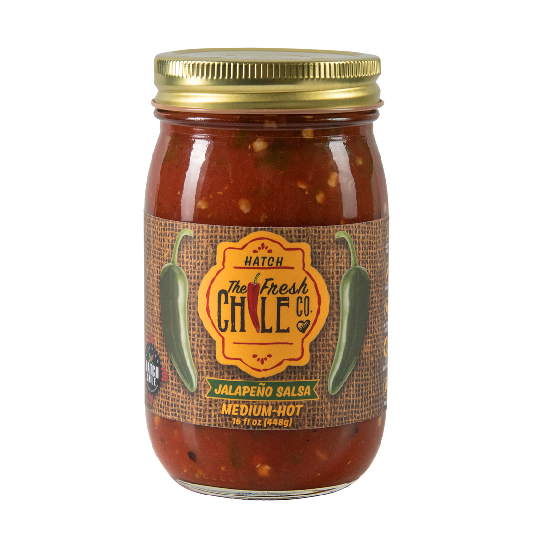 A glass jar of Hatch Jalapeño Salsa labeled "The Fresh Chile Co. Hatch" in medium-hot spiciness, sealed with a metal lid, isolated on a white background. Perfect for New Mexican salsa recipes.