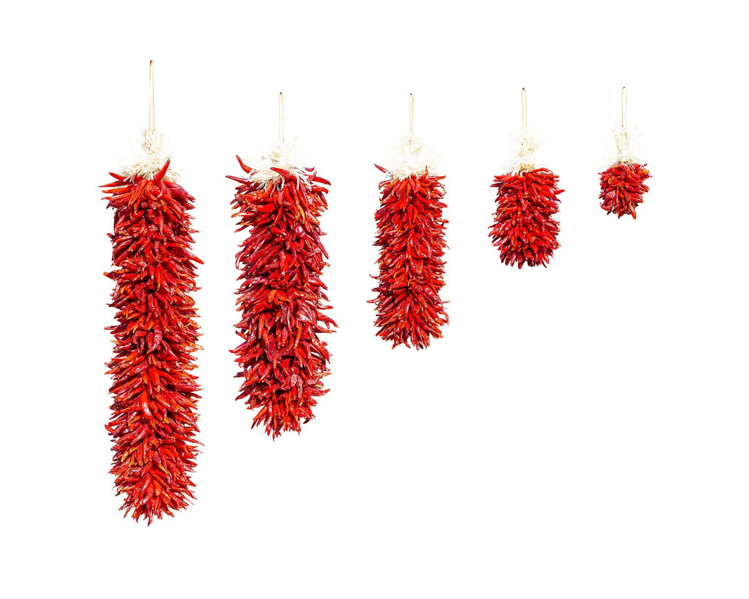 Five strings of Chile Pequin Ristras hanging against a white background, decreasing in length from left to right.