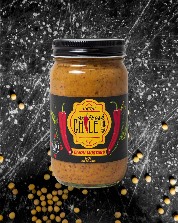 A jar of BBQ Sampler from the fresh chile co., labeled "hot", with hatch chile illustrations, against a black background with scattered mustard seeds. Part of our Variety Gift Packs collection.