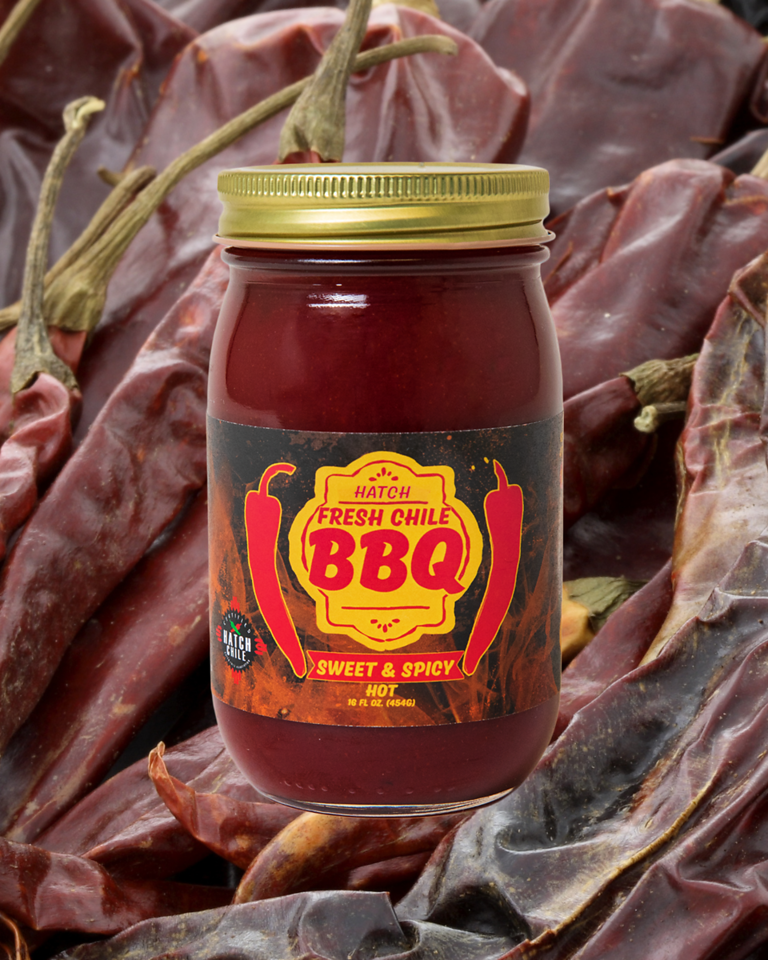 A jar of BBQ Sampler fresh chile BBQ sauce labeled "sweet & spicy" set against a backdrop of dried red chili peppers.