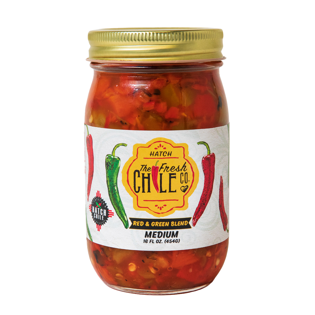 Sentence with the replaced product name: A glass jar of Hatch Red & Green Chile salsa featuring a mix of flame roasted Hatch red and green chiles. The label displays colorful illustrations of peppers with text indicating it's a medium-spiced.