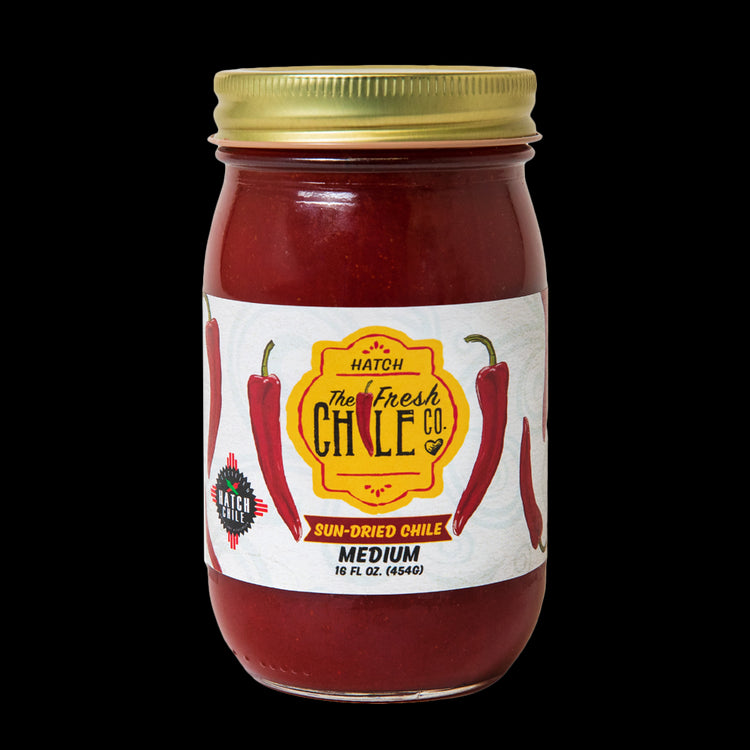 A jar of Sun-Dried Red Chile sauce, medium spice level, with a label featuring red chili peppers. The jar contains 16 oz. of sauce.