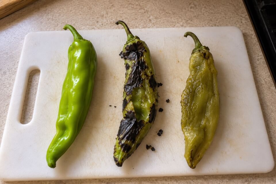Fresh, blistered and peeled green chile pods on a cutting board